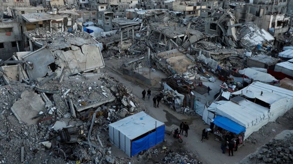 Palestinos caminham em meio a destroços em Khan Younis, na Faixa de Gaza (Foto: Ramadan Abed/Reuters)
